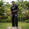 Nigerian male model wearing black skull and flag graphic wide-leg sweatpants – full body lifestyle shot