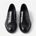 Pair of glossy black penny loafers on a plain white background