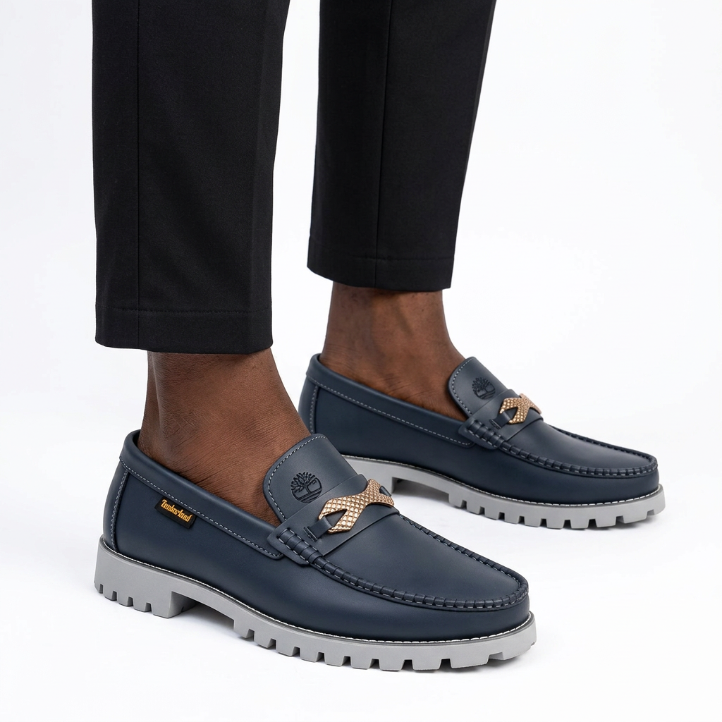 Male model wearing navy gold-trim grey lug-sole loafers, both shoes visible on white