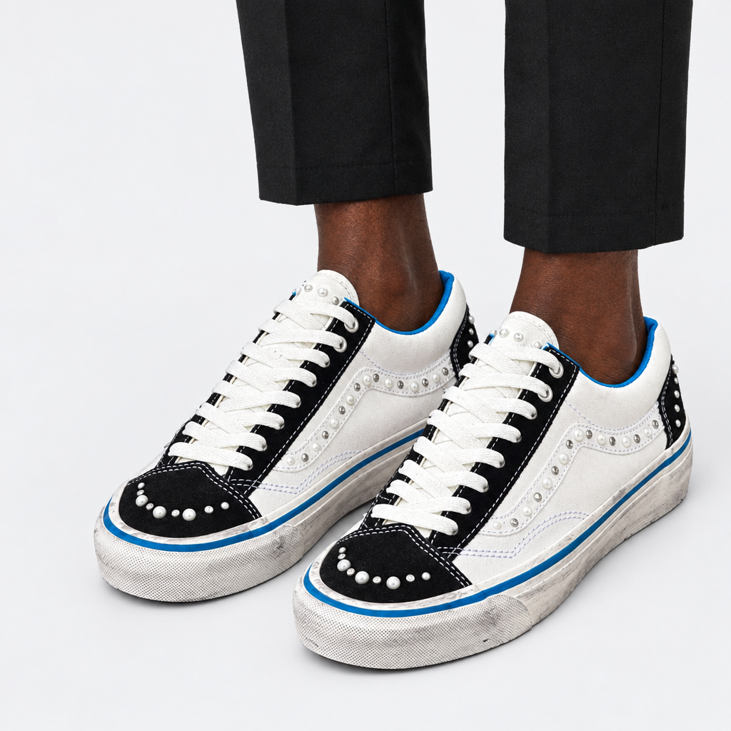 Adult wearing white-and-black embellished sneakers with blue details