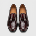 Men's burgundy patent leather penny loafers, straight-on view of the pair