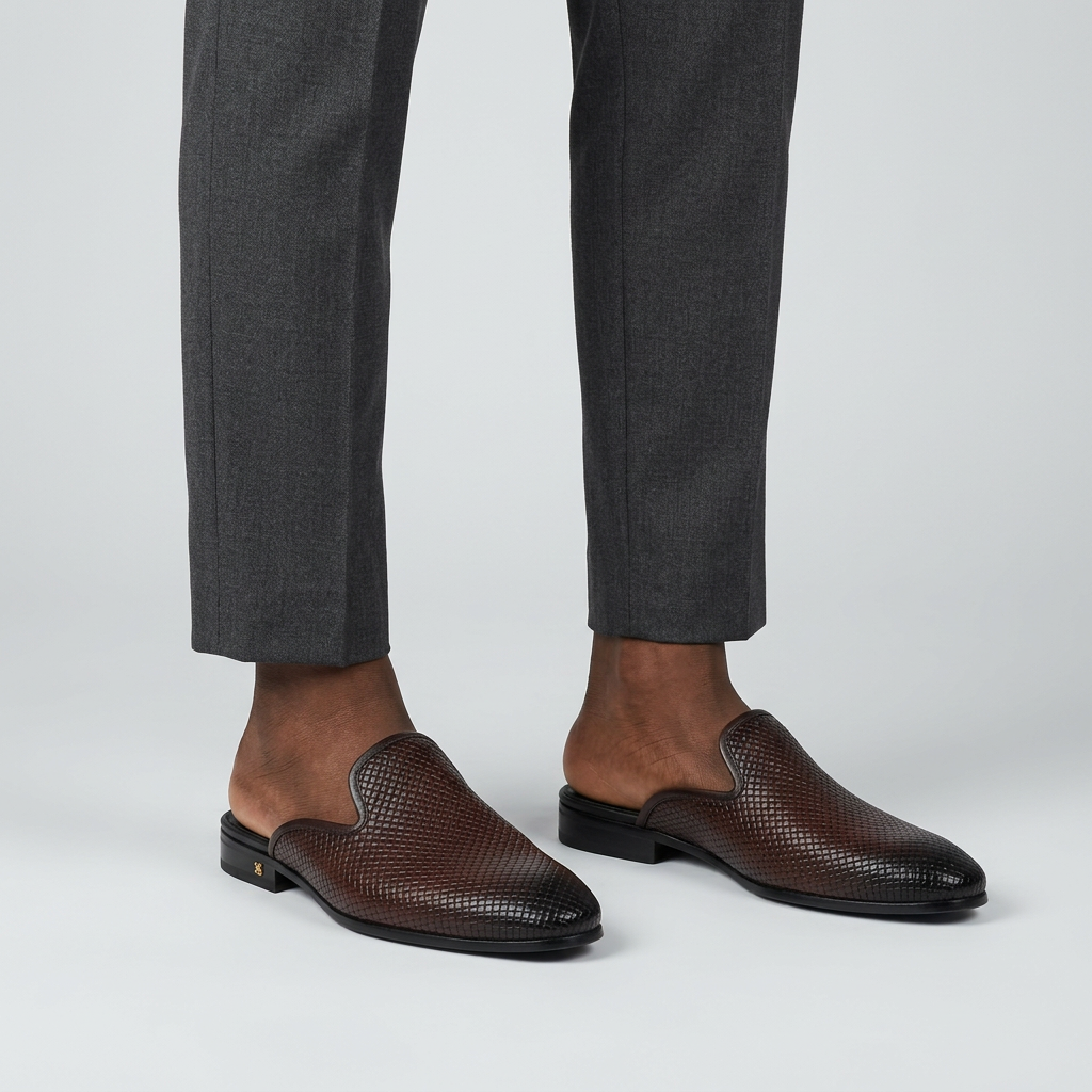 Man wearing brown woven-leather backless mules with heel on a plain studio background