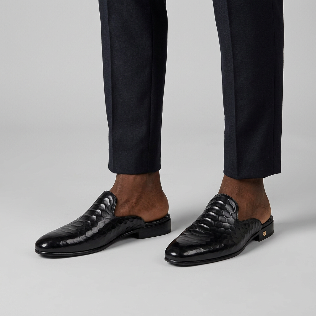 Man wearing black quilted-texture backless mules with heel on a plain studio background