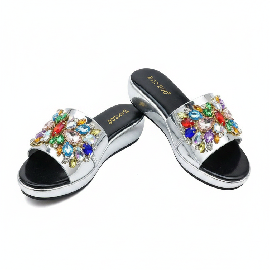 Ghost mannequin pair view of silver metallic wedge slide mules with multicolour gemstone rhinestone floral strap