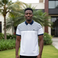 Nigerian male model wearing white striped yoke polo shirt with navy collar and cuffs in garden setting