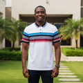 Nigerian male model wearing men's white polo shirt with multicolour chest stripe, garden setting
