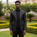 Nigerian male model wearing all-black floral damask jacquard tuxedo three-piece suit