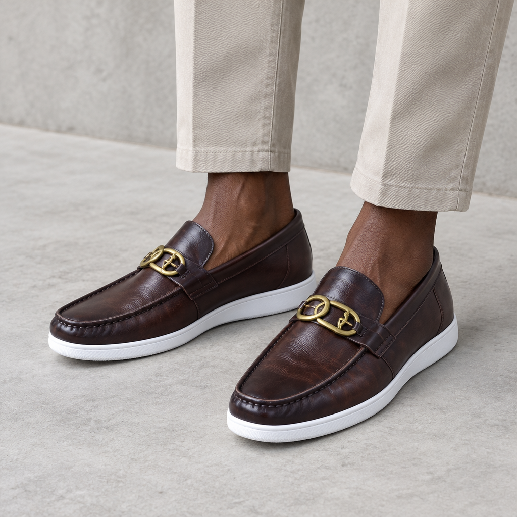 Dark brown loafers with gold-tone detail worn on both feet