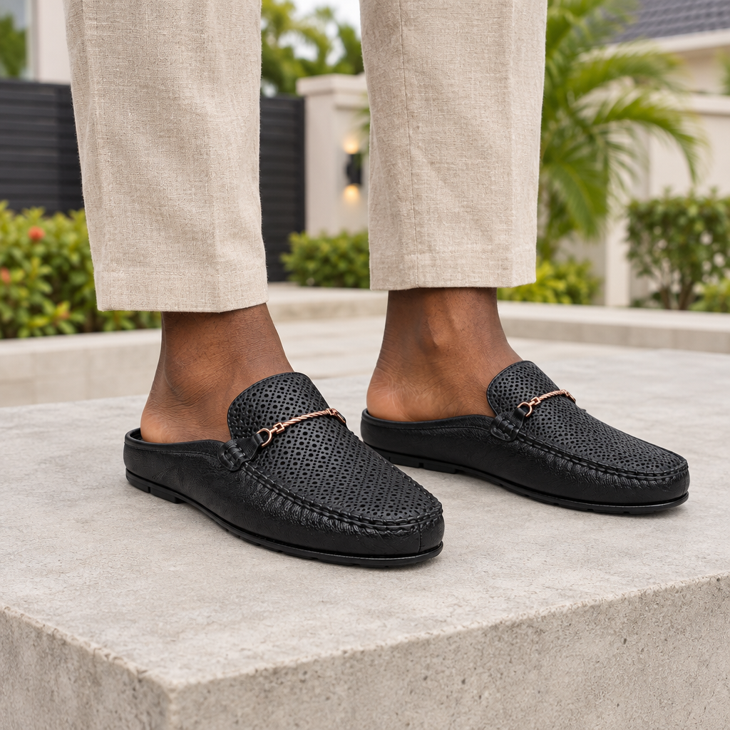Man wearing black perforated backless mule slippers with beige linen trousers