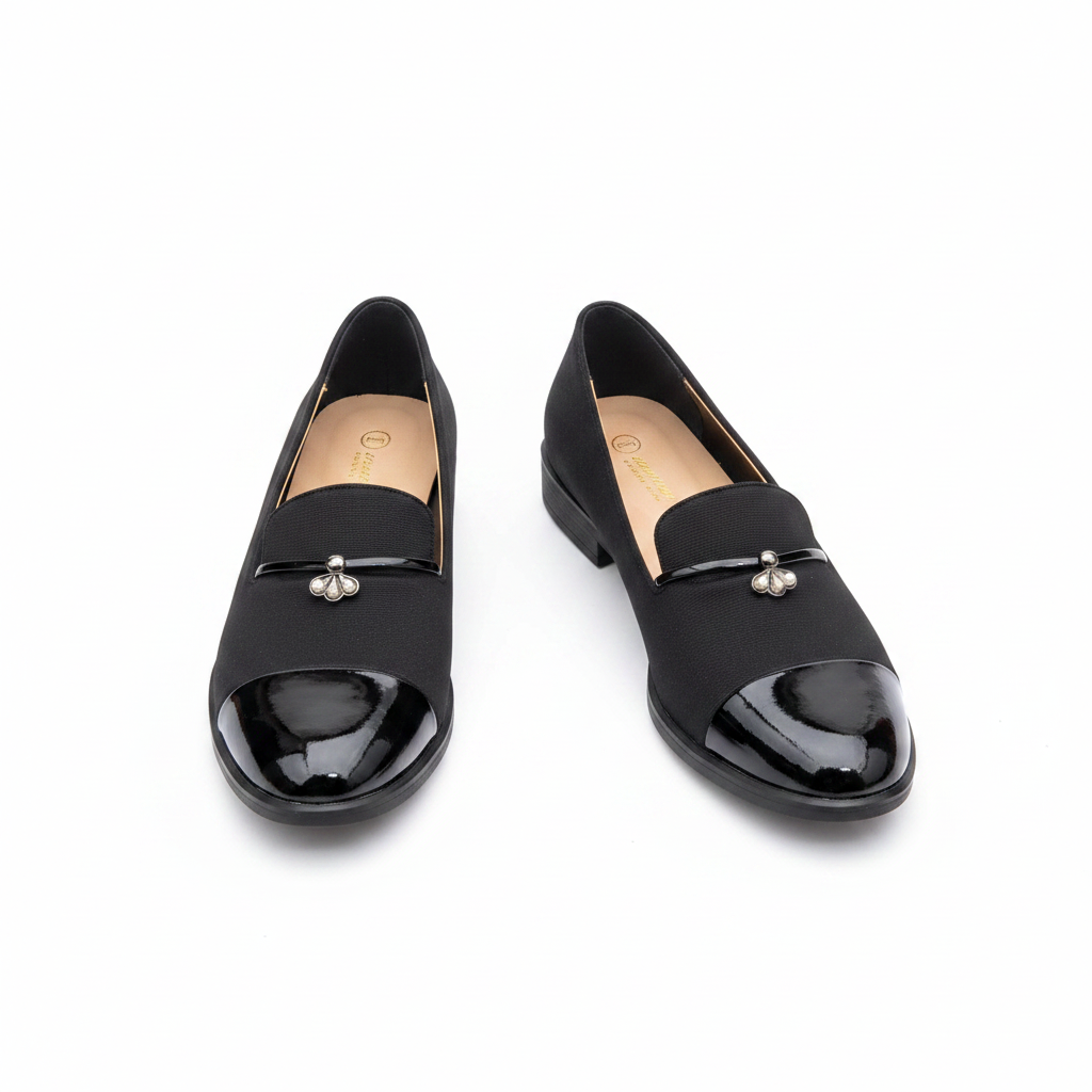 Black two-tone loafer flat with patent toe cap and pearl brooch — clean pair product shot