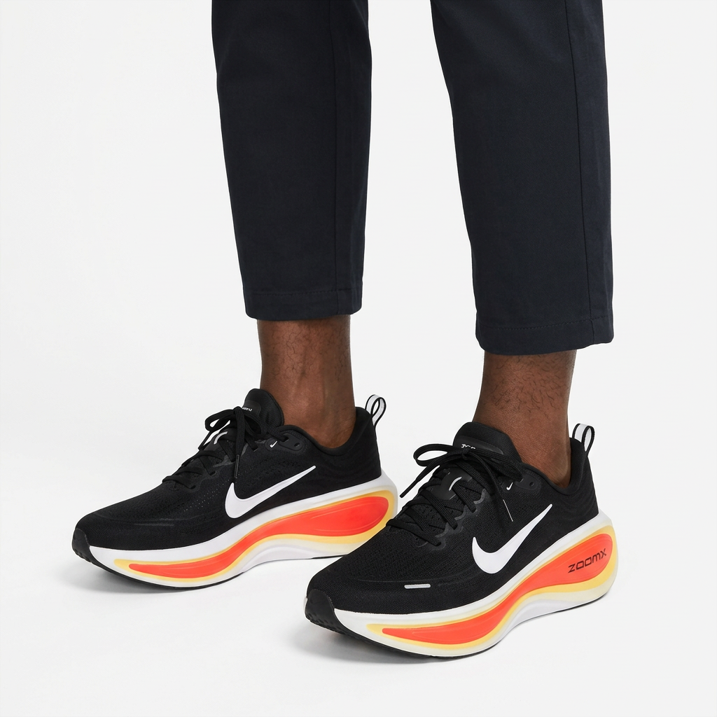 Pair of black sneakers with red-and-yellow soles properly worn on both feet