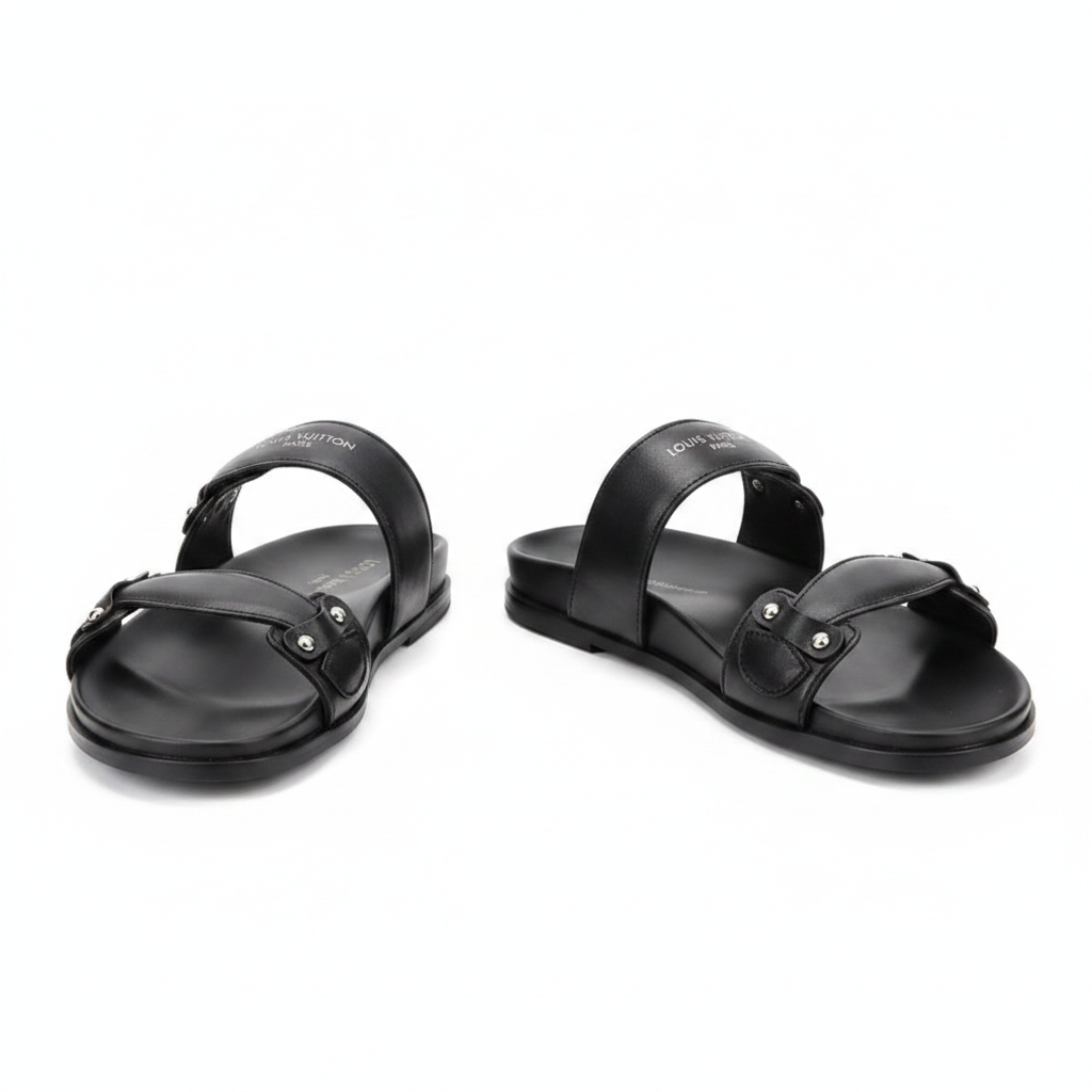 Pair of black double-strap flat slide sandals with silver stud accents on white background
