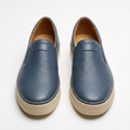 Slate blue pebbled slip-on shoe pair with cream soles and tan interiors