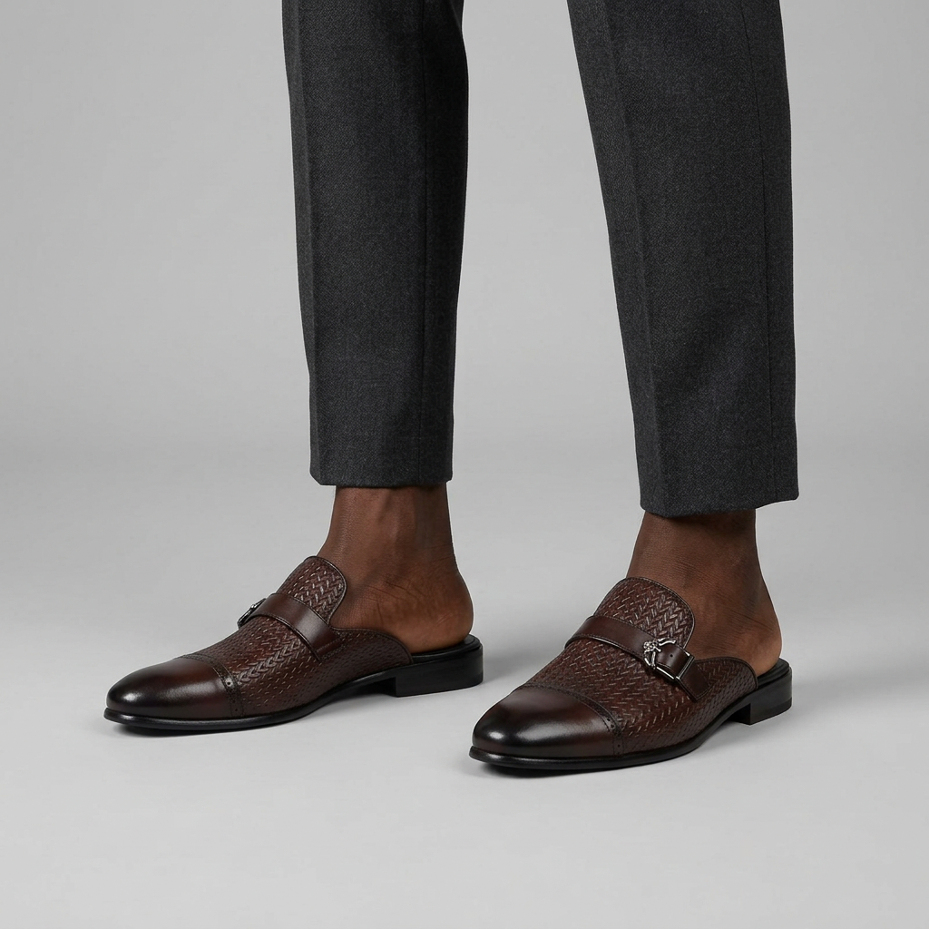 Man wearing brown woven-textured backless mules with buckle on a plain studio background