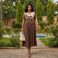 Nigerian female model wearing chocolate brown and cream pleated midi gown in upscale garden setting