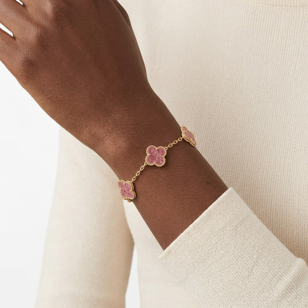 Gold-tone pink clover bracelet worn on a Black adult wrist