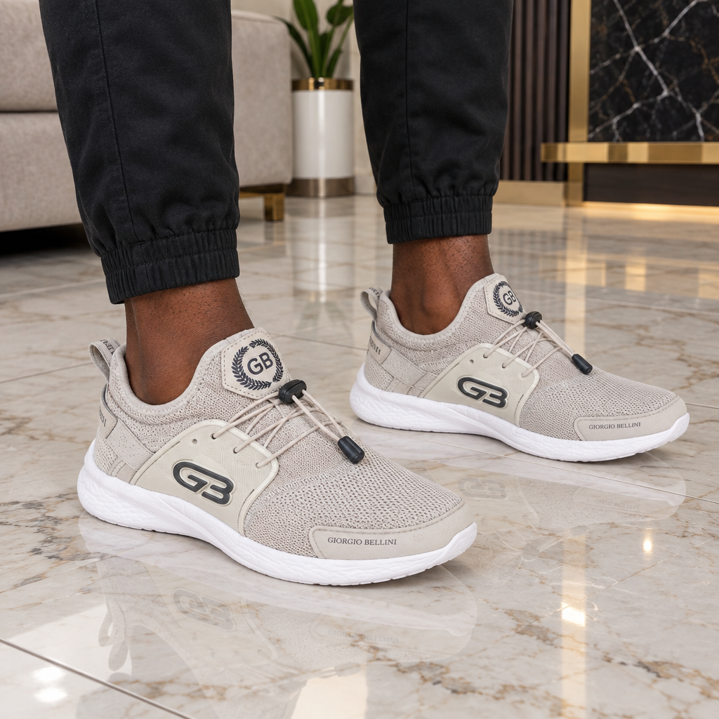 Both feet wearing light grey mesh men's trainers on marble floor