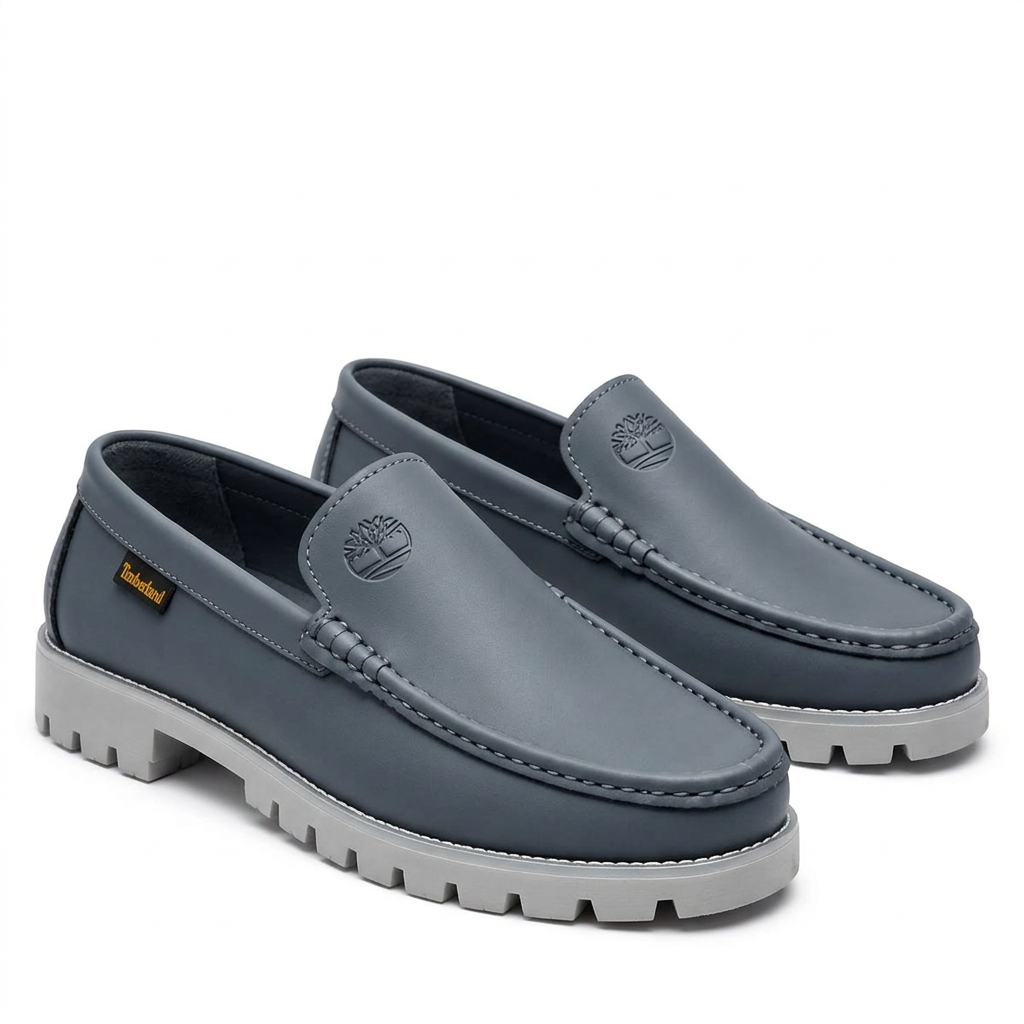 Pair of slate grey moc-toe loafers with light grey lug soles on a white background