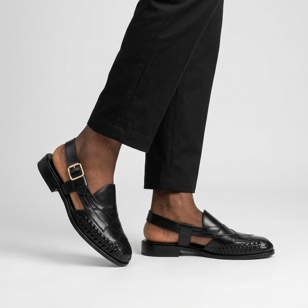 Men's black slingback sandals with woven lattice detail worn with relaxed-fit trousers, plain studio background