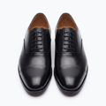 Straight-on black smooth cap-toe Oxford shoes with dark laces