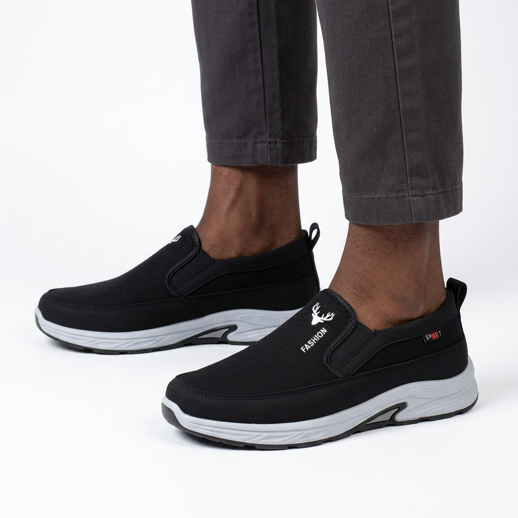 Black slip-on shoes worn on both feet by a Black male model on white