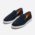 Navy slip-on loafers with white soles and tan interiors