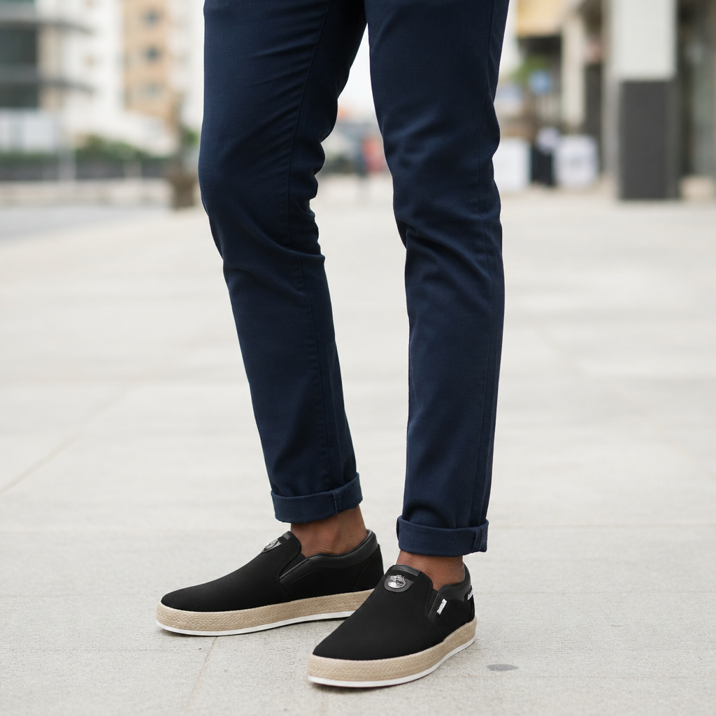 Model wearing black canvas slip-on sneakers with beige woven soles