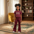 STEEZU girls' burgundy co-ord set with pearl "LOVE IS GOOD" graphic tee and flare pants with gold micro-dot pattern.