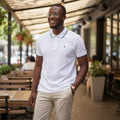 STEEZU white polo shirt with navy blue tipping on collar and sleeves, featuring a small navy crown embroidery on the chest.
